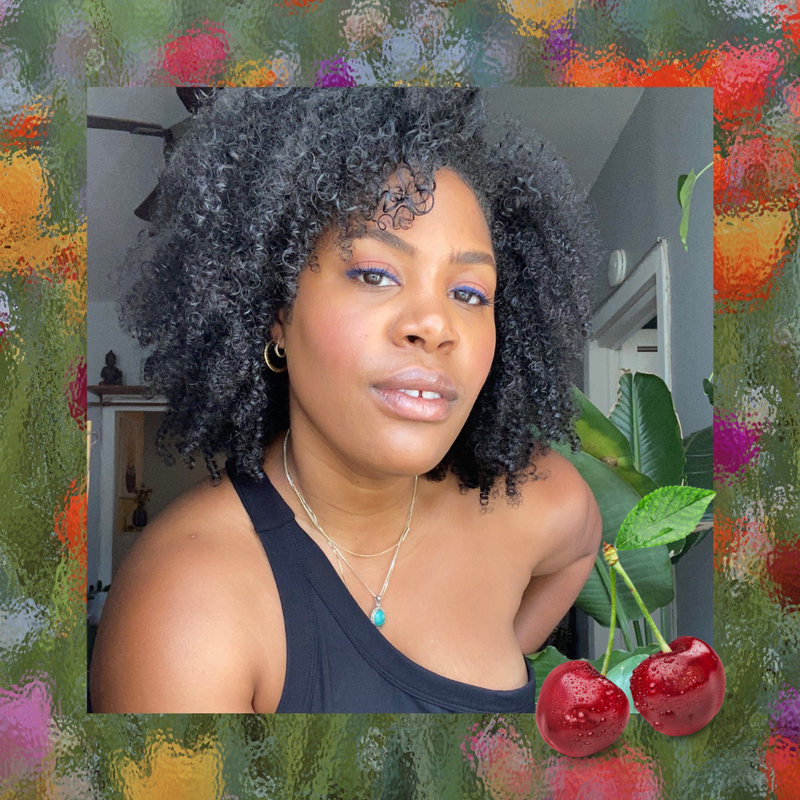 Black woman with natural hair and blue eyeliner against a floral background