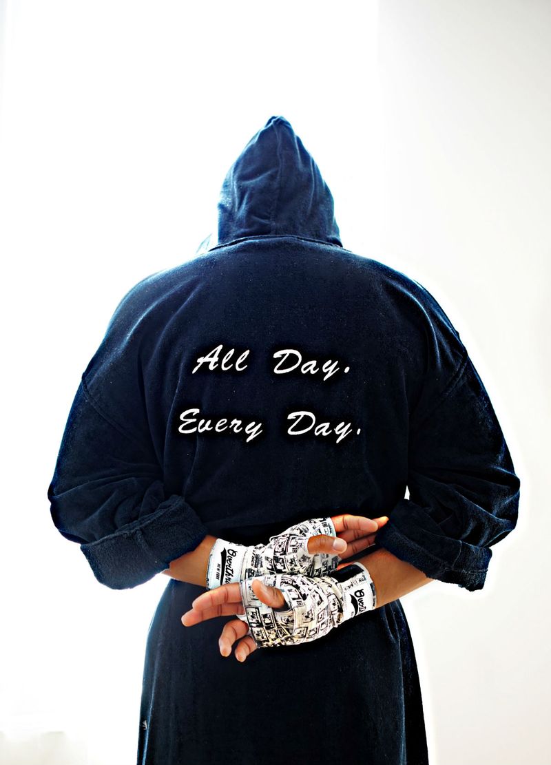 Man with arms crossed behind his back. Navy robe with letters "All Day, Every Day" in cursive. 