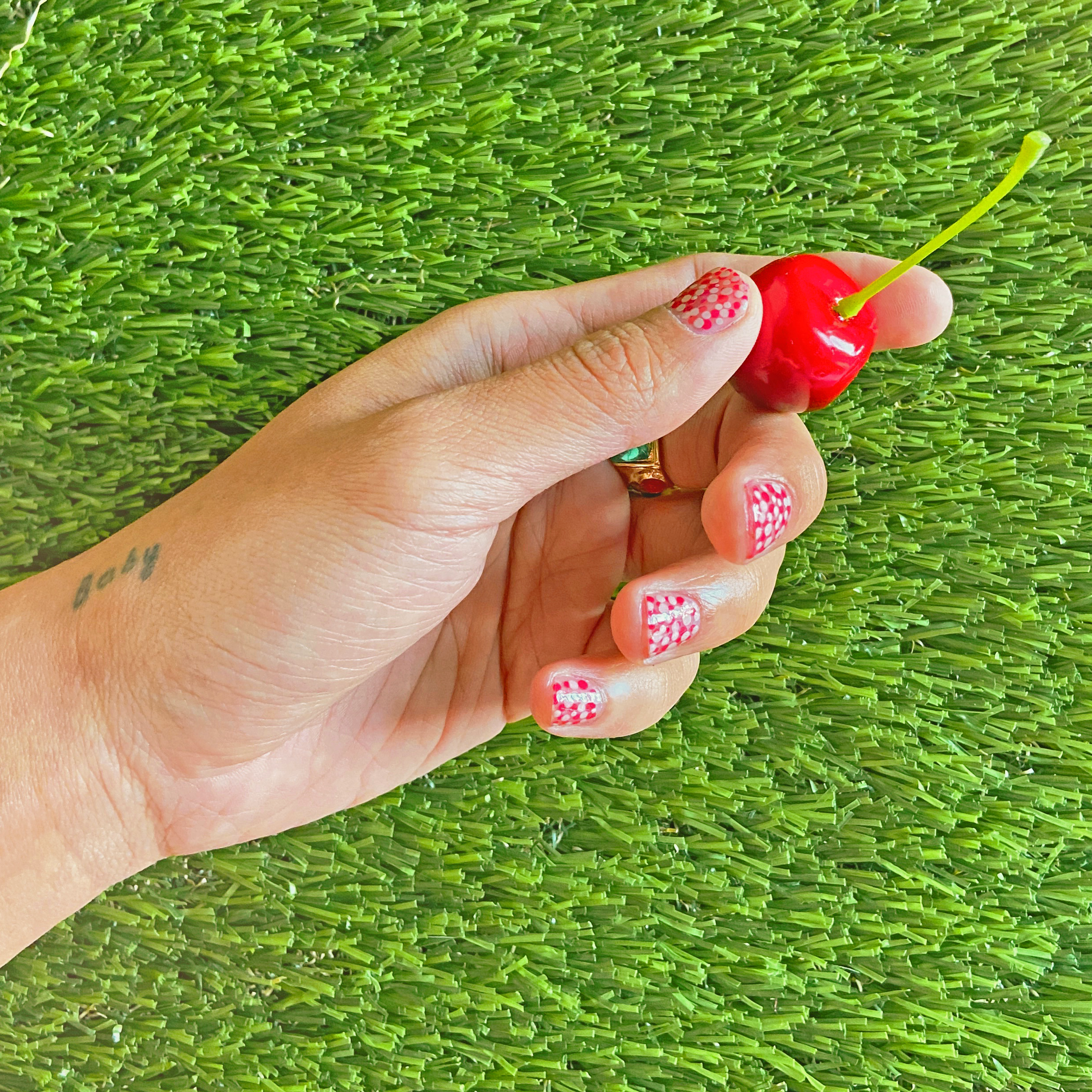 Male hands with tattoos, polka dot mushroom-inspired nail art and gold rings using Harry Styles' Pleasing Shroom Bloom polish