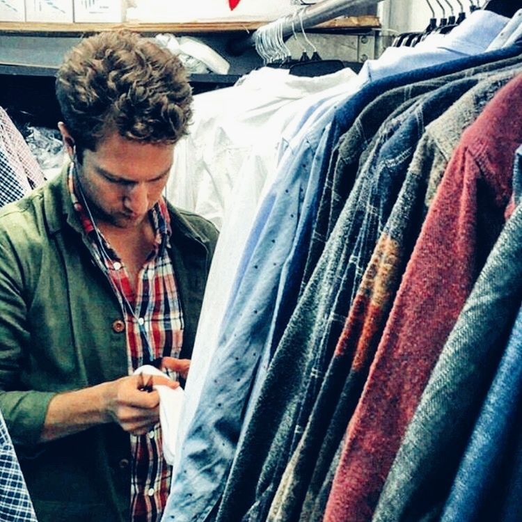 Guy with fluffy hair looking at clothe's tag.