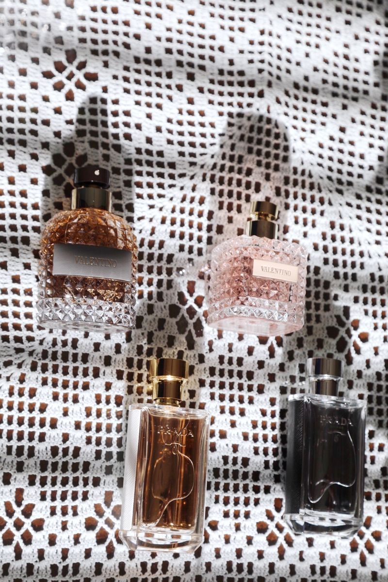 Valentino's and Prada's fragrances laid out on a knit. 