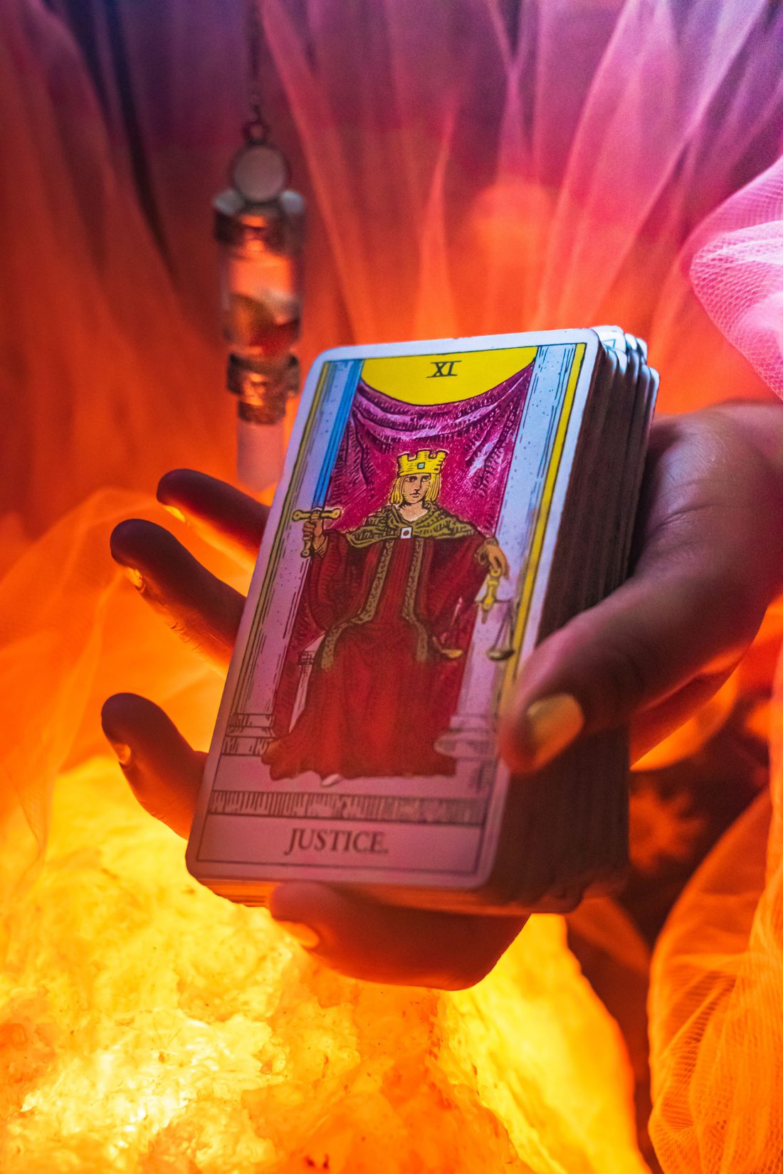 hand holding the justice tarot card over a salt lamp