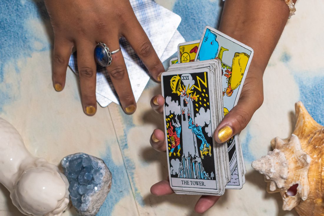 hand holding the tower card surrounded by crystals