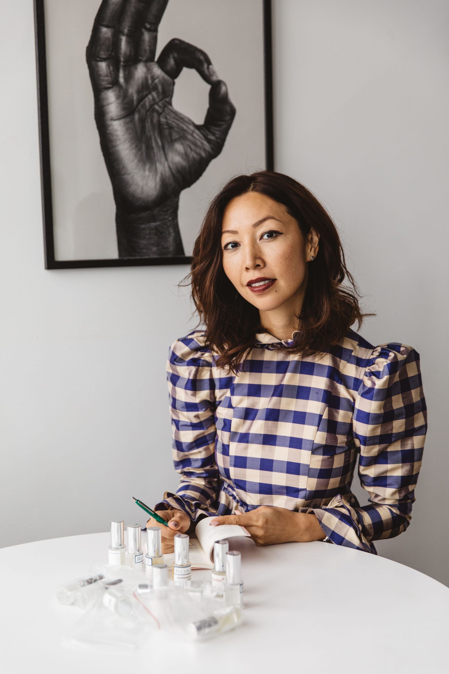 Bee Shapiro, founder of Ellis Brooklyn, sits at a white table with fragrance samples. She holds a small notebook and pen.